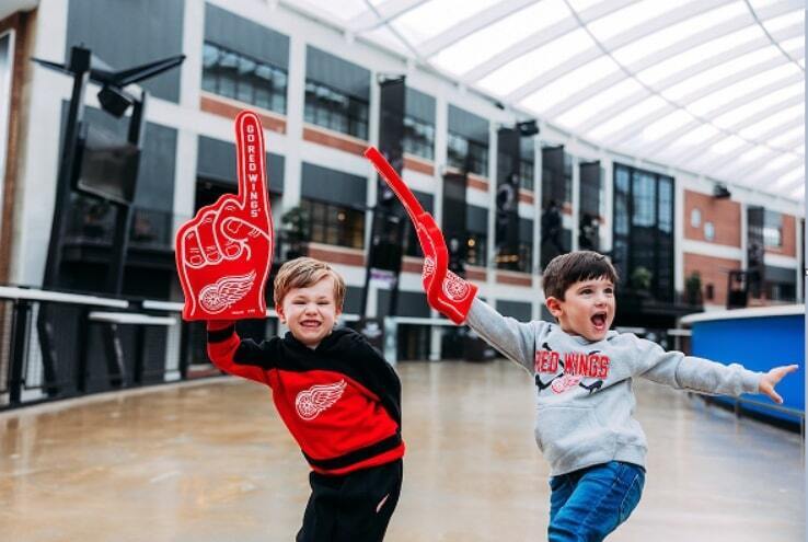 Two children standing inside arena smiling and happy with foam #1 finger on their right hands.